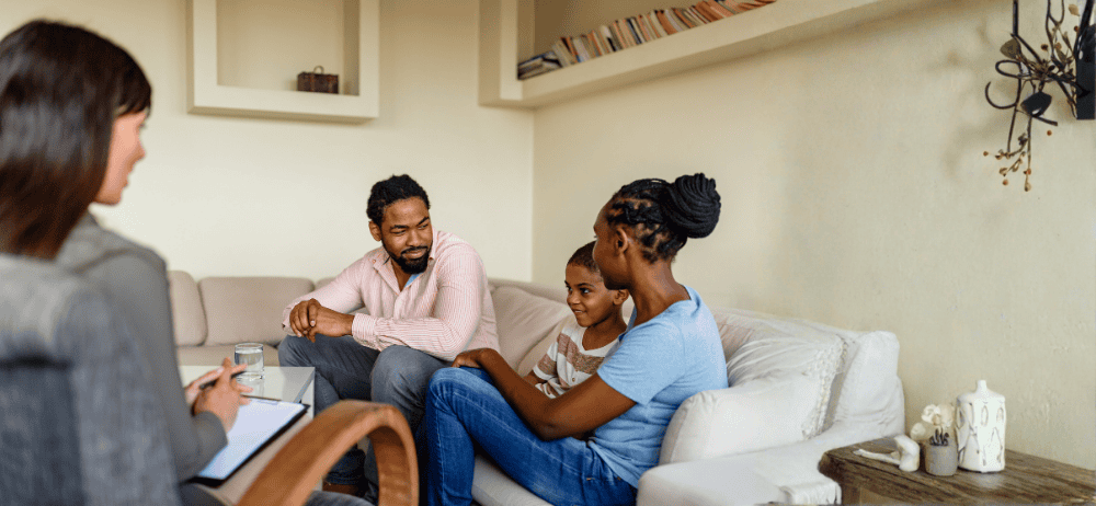 Therapist sitting with father and children in child and adolescent therapy appointment