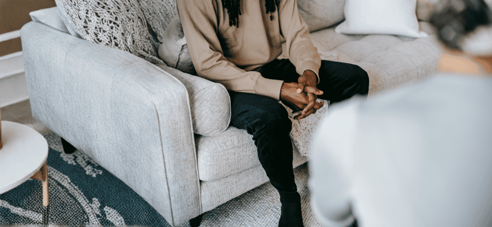 Therapist sitting with client. Client is holding their hands together.