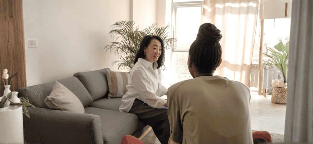 Therapist sitting with client. Client is smiling opposite of the therapist.