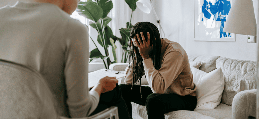 Therapist sitting with client holding his head in his hands