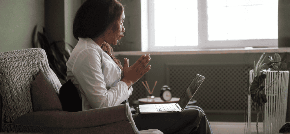 Woman sitting down with laptop on her lap and hands together