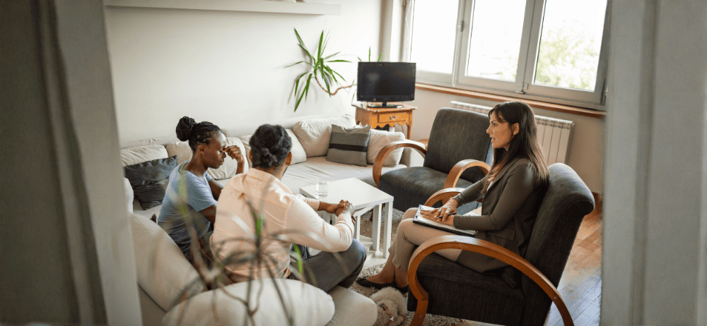 Therapist sitting with a couple in a session woman is covering eyes with fingers in frustration