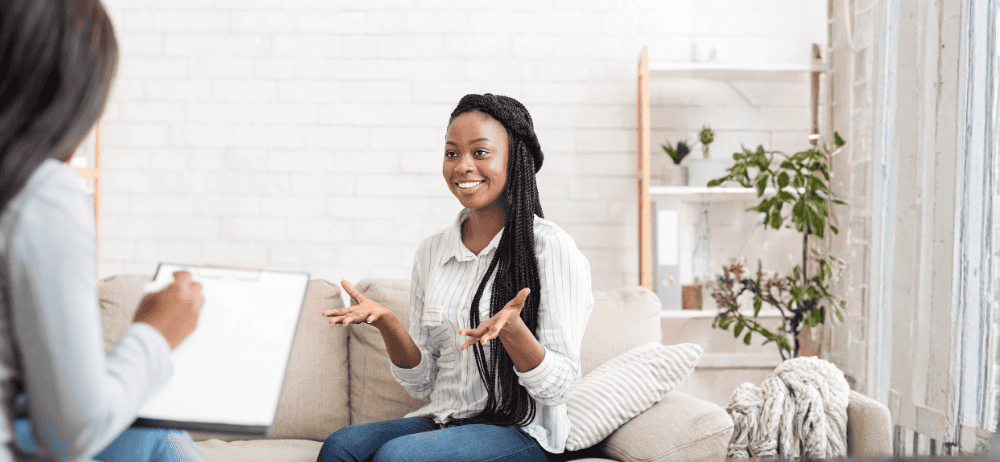 Therapist sitting with happy client who looks like she is trying to explain something enthusiastically