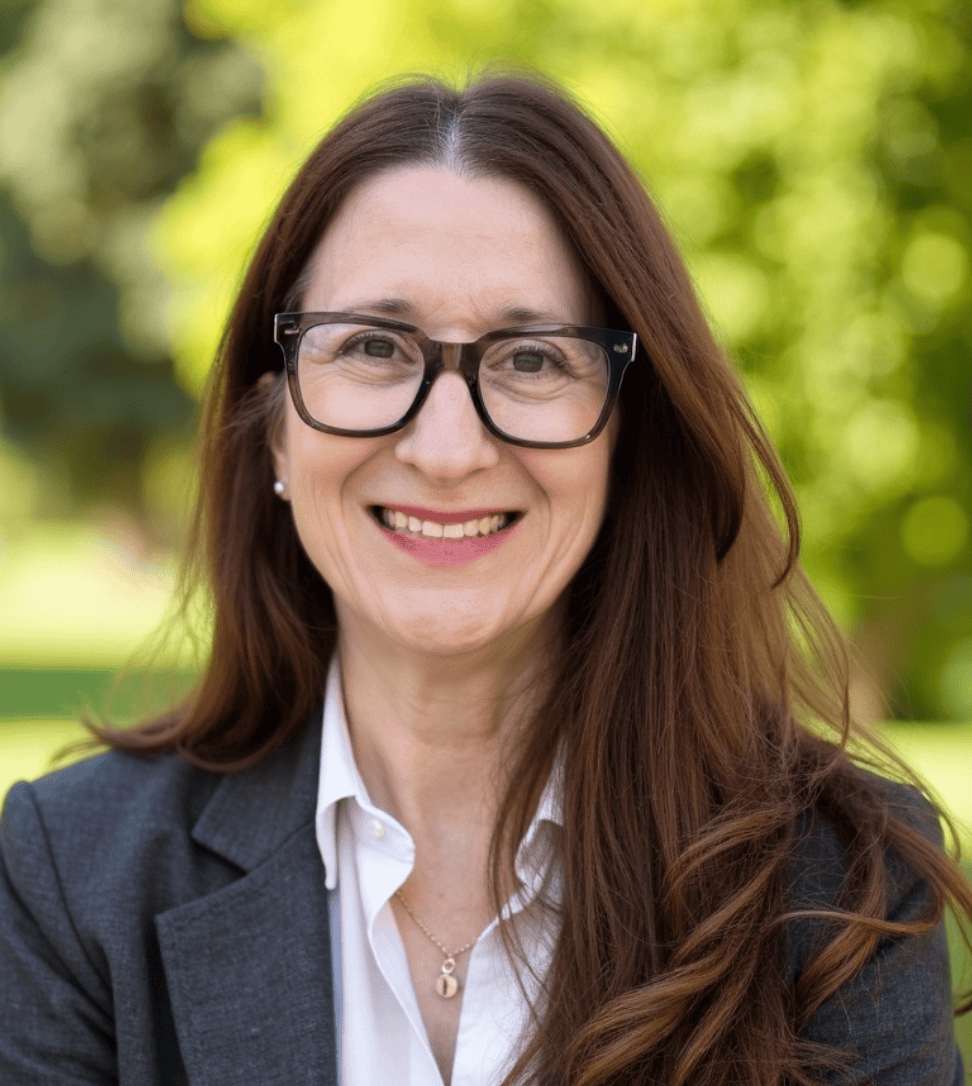 Monica Ferraro Headshot smiling in front of greenery