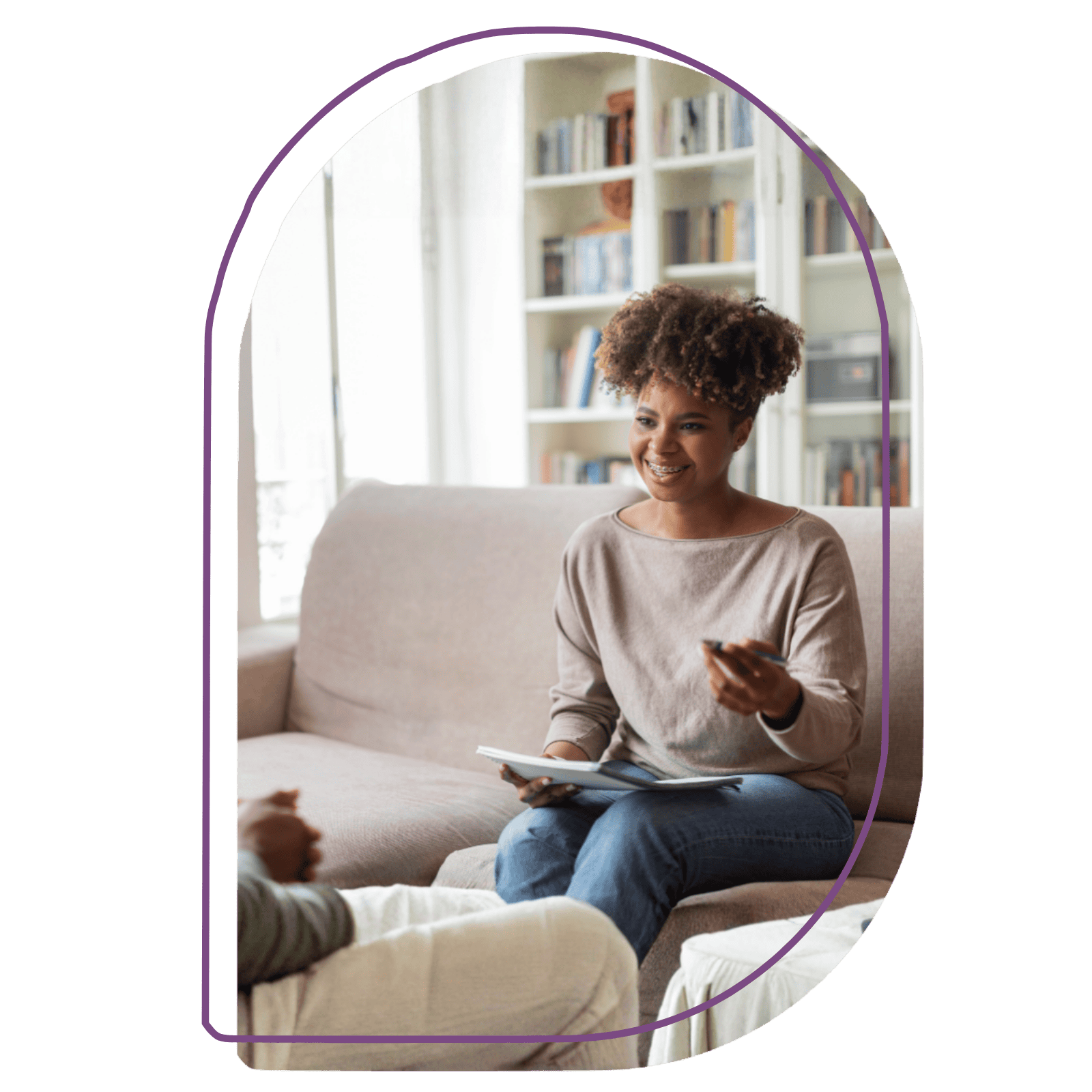 Therapist sitting with client smiling and holding a pen and journal