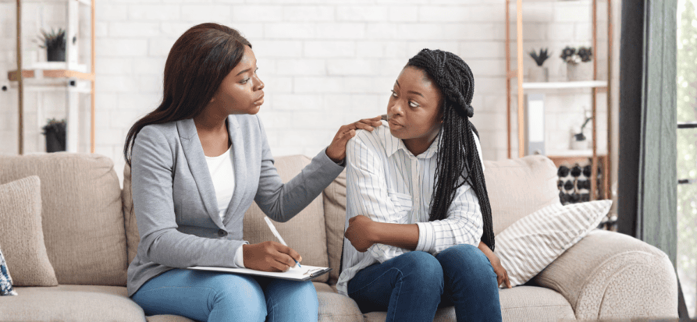 therapist showing compassionate care for infertility client on a couch with hand on shoulder