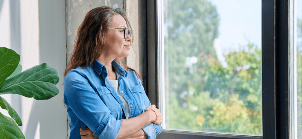 Woman looking out window contemplating infertility and mental health